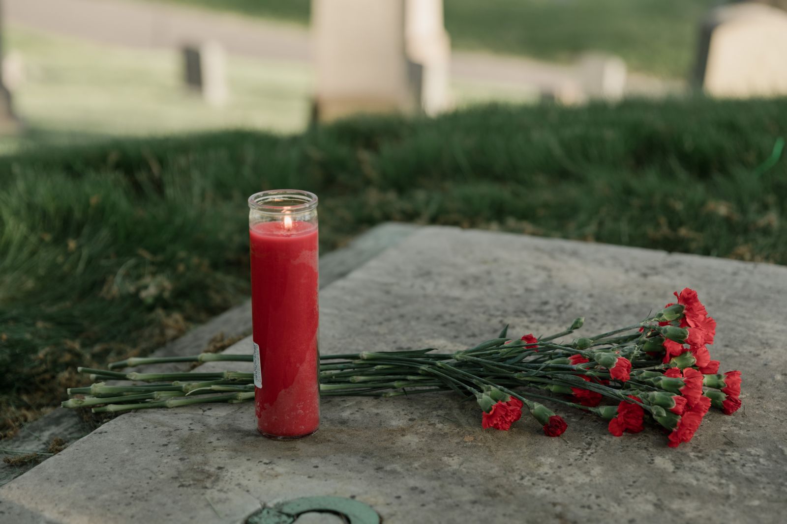 Свеча и красные цветы в память об умершем